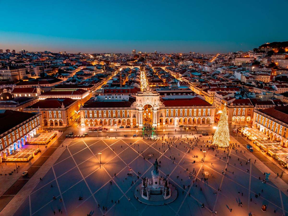 Aerial view of Praça do Comércio at night with glowing lights and a decorated Christmas tree