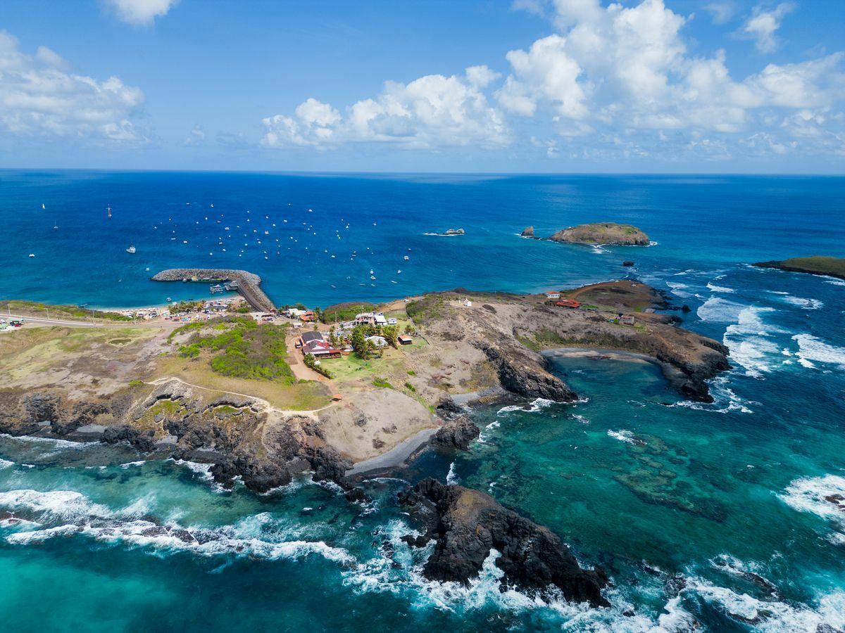 Aerial view of a rocky island coastline with turquoise coves and deep blue ocean
