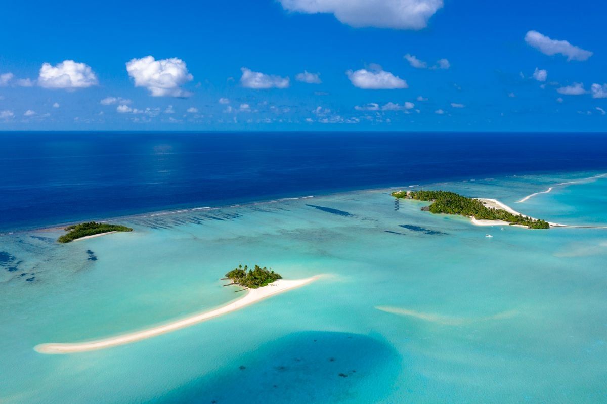 Aerial view of small sandy islands surrounded by shallow turquoise and deep blue sea