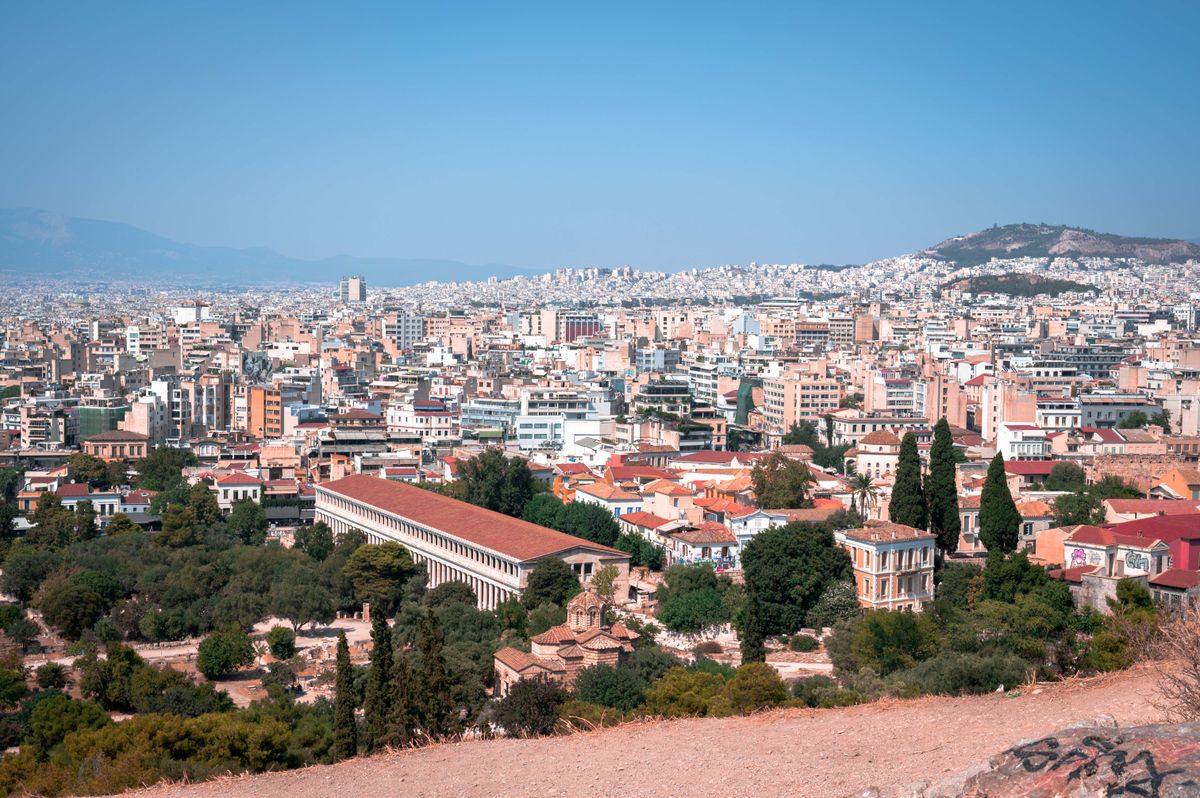 Athens cityscape with dense buildings, red roofs, and ancient structures under a clear sky