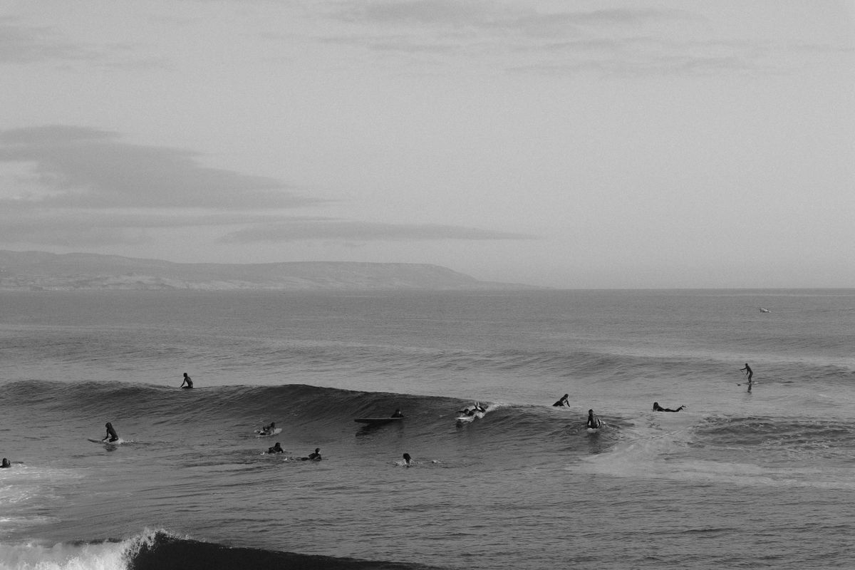 Black and white scene of surfers spread across small rolling waves near shore