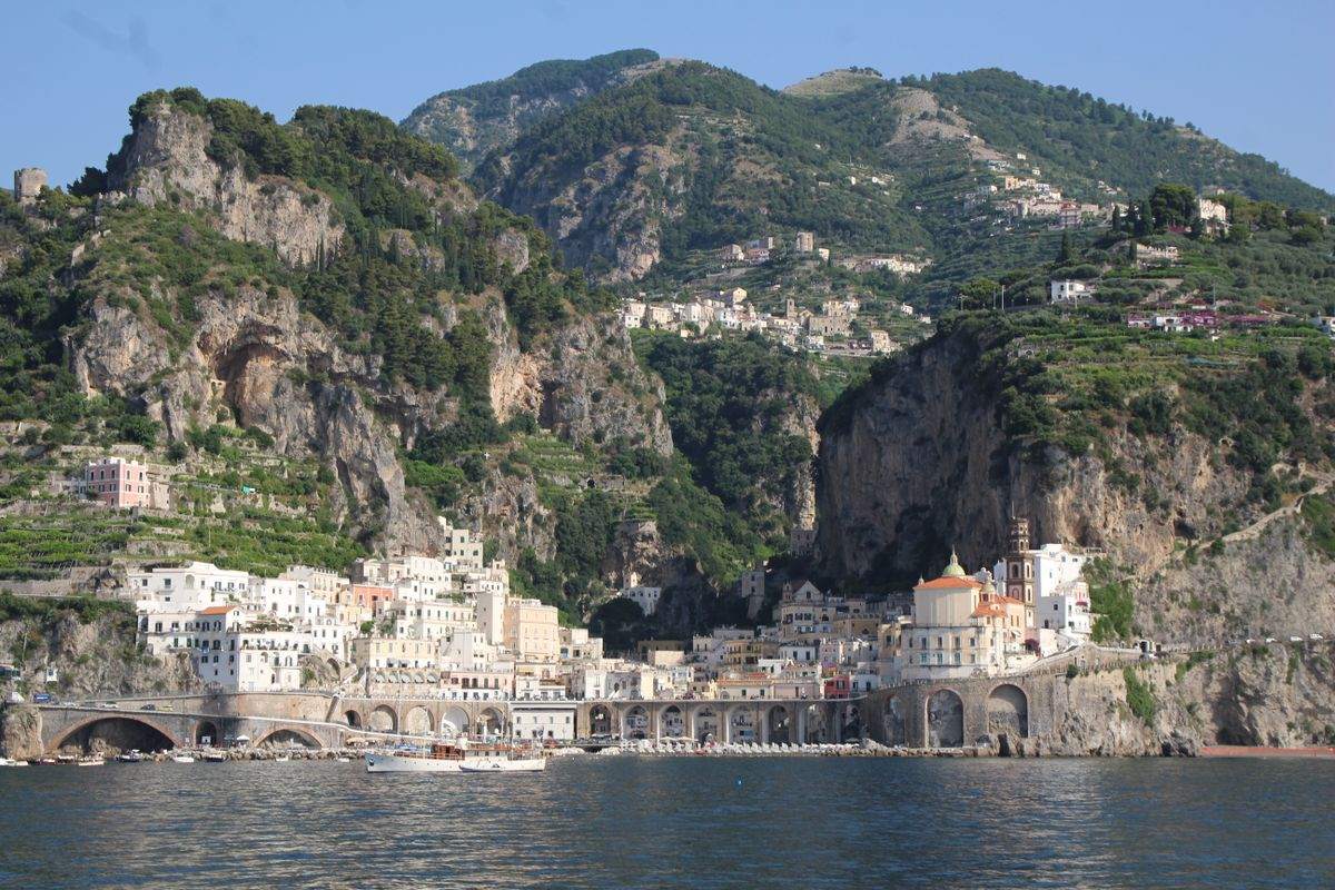 Coastal town beneath steep cliffs and green mountains on the Amalfi Coast
