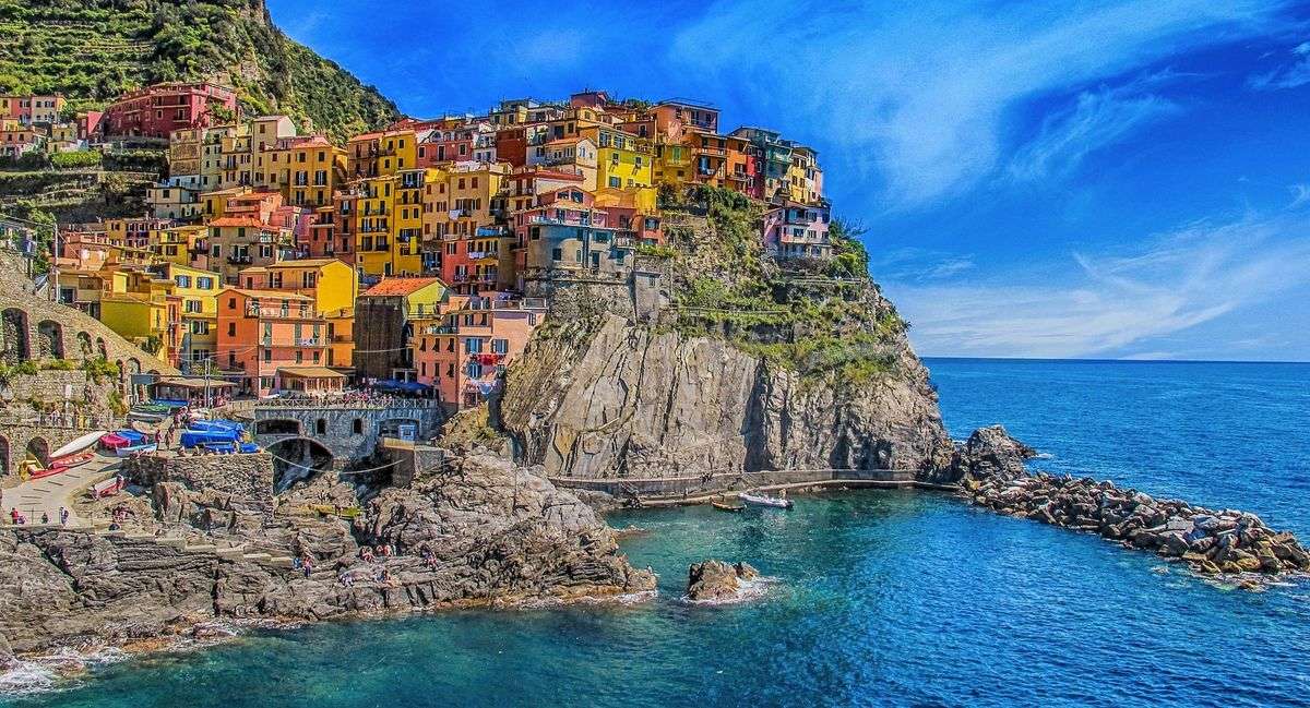 Colorful cliffside houses in Manarola above a rocky cove and bright blue sea