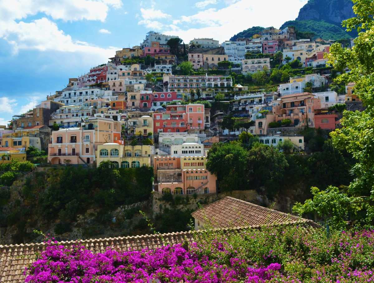 Colorful hillside houses in Positano framed by greenery and purple flowers