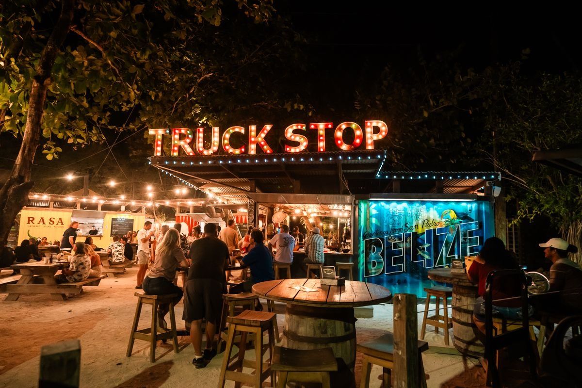 Crowd gathered outside a lit Truck Stop venue at night in San Pedro, Belize