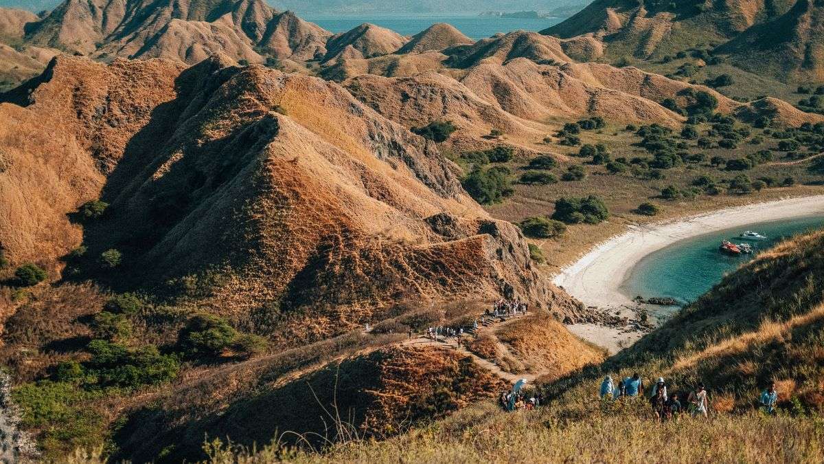Dry rolling hills and a curved white sand beach on Padar Island