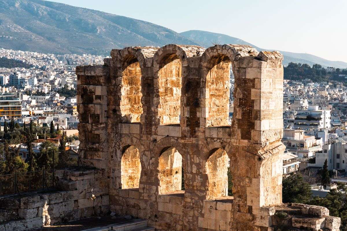 Odeon of Herodes Atticus stone arches with Athens buildings and mountains behind