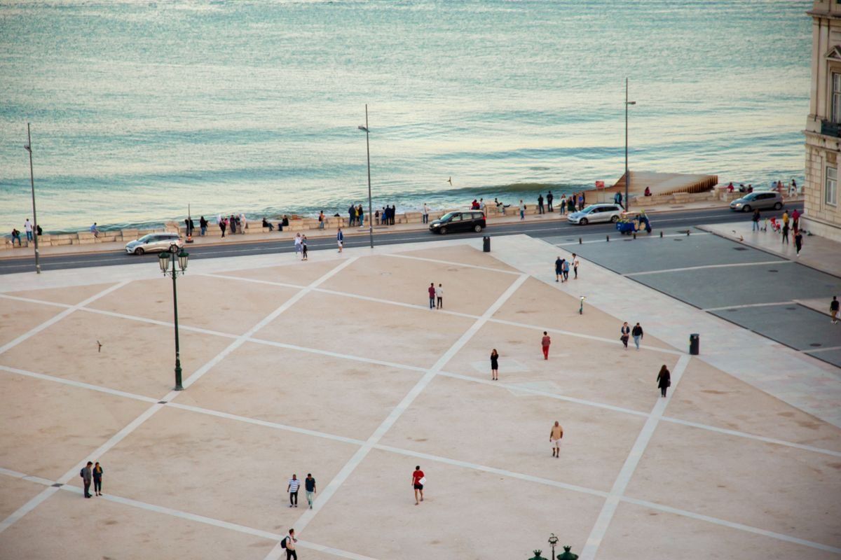 People scattered across a large waterfront square beside the river