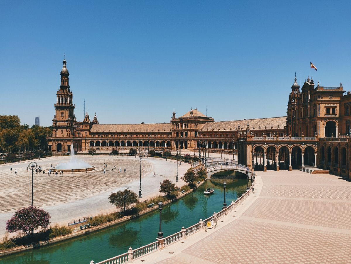 Plaza de España in Seville with canal, fountain, and ornate buildings in sunlight