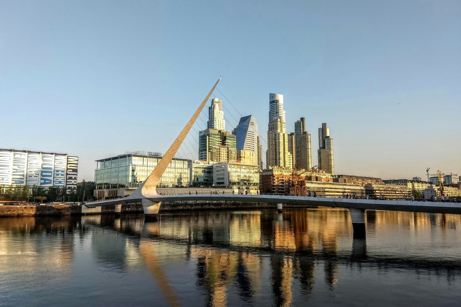 Puente de la Mujer footbridge and Puerto Madero skyscrapers reflected in the water at sunset in Buenos Aires