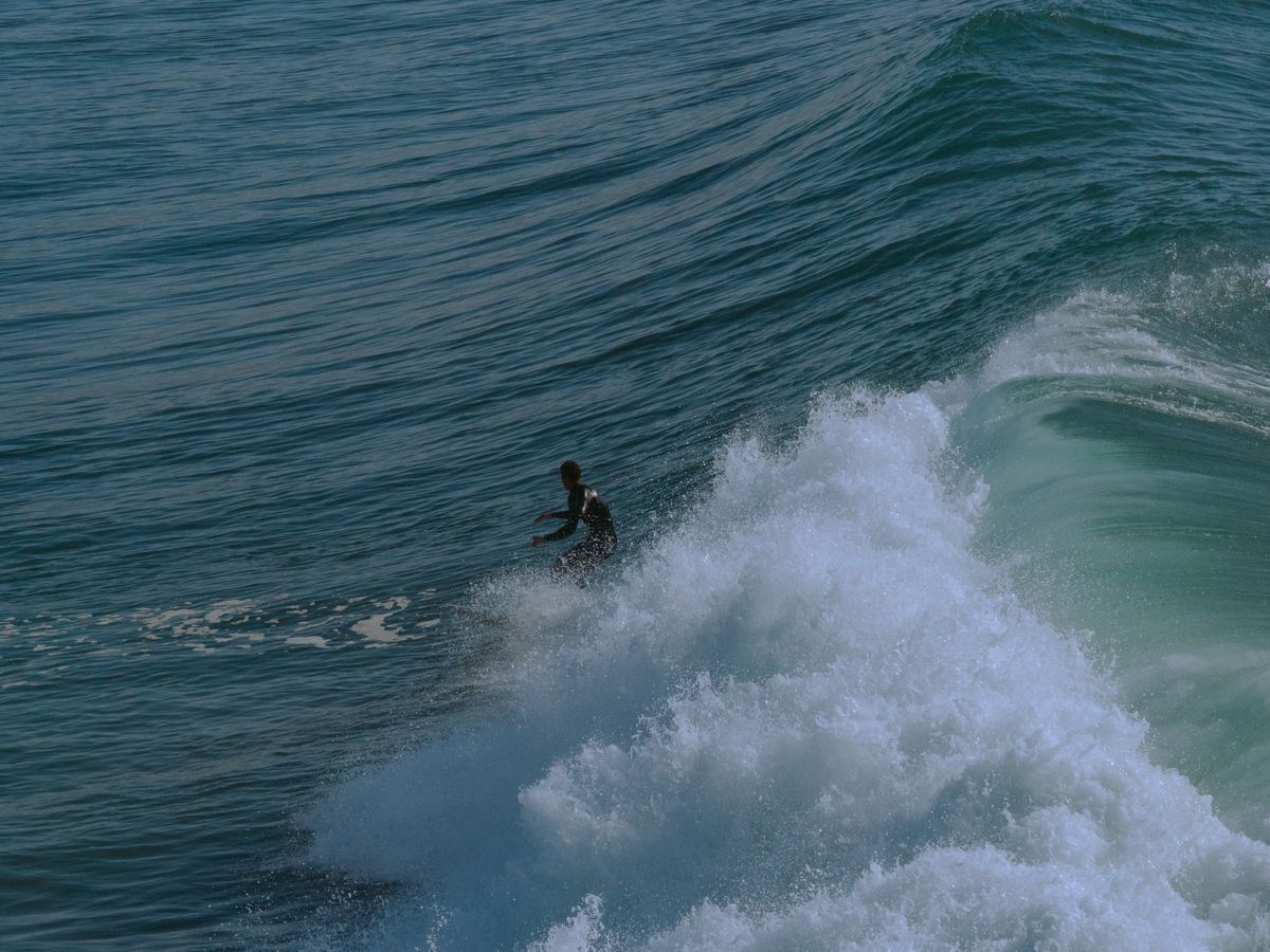 Single surfer carving beside a steep breaking wave