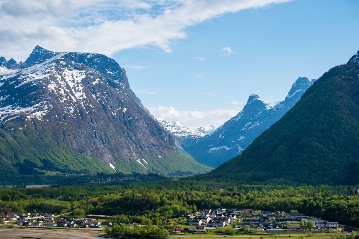 Snow-capped mountains rising above a small town and green valley in Åndalsnes