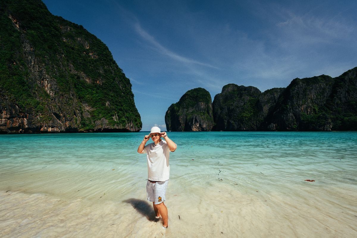 Tourist standing in shallow water on a white sand beach at Maya Bay
