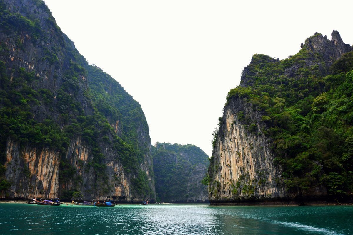 Turquoise bay framed by towering limestone cliffs covered in dense greenery