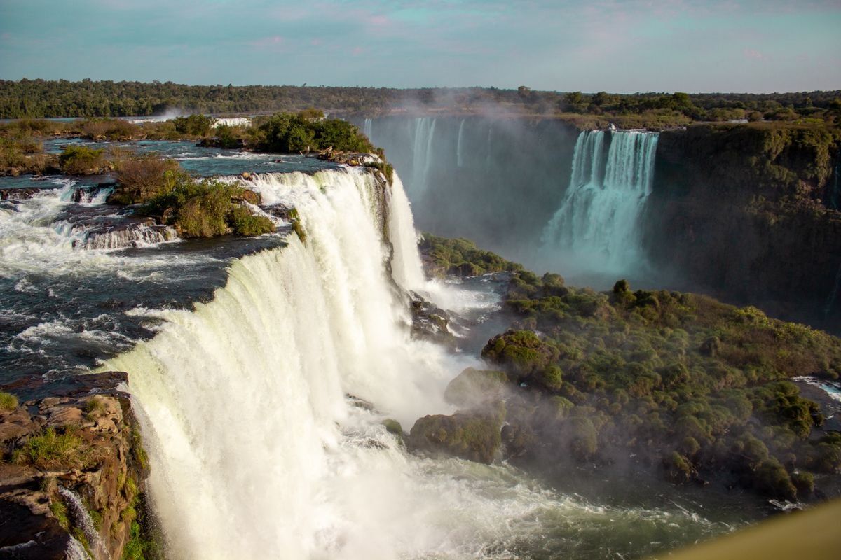 Wide view of Iguazu Falls with powerful cascades, mist, and forested cliffs