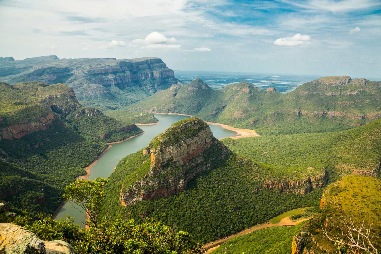 Aerial view of a dramatic canyon with a winding river cutting through green mountains in South Africa