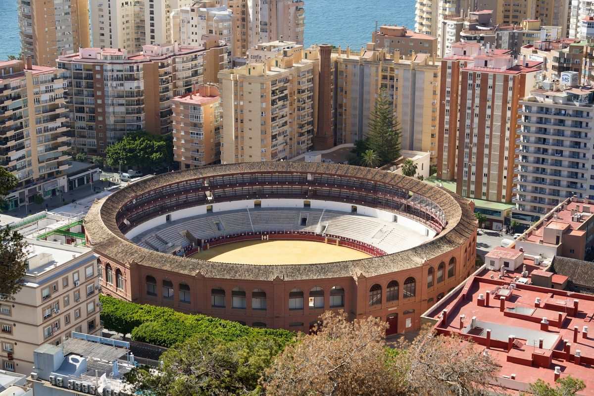 Aerial view of Málaga bullring surrounded by apartment buildings near the waterfront