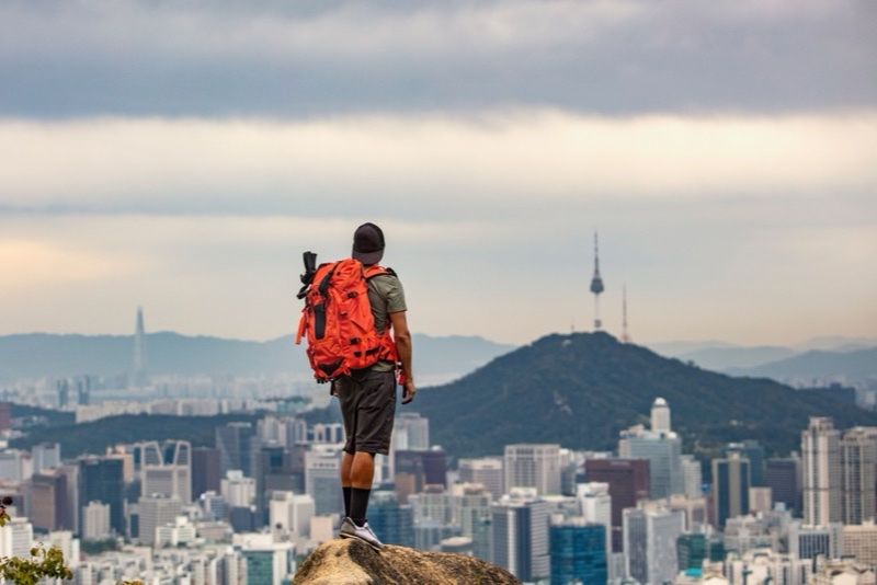 Hiker with backpack overlooking a city skyline
