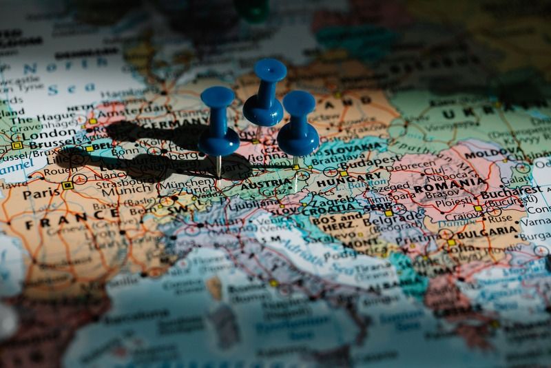Three blue pushpins marking travel destinations on a map of Central Europe