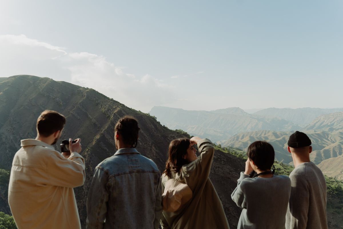 Five people looking at a mountain landscape, some taking photos