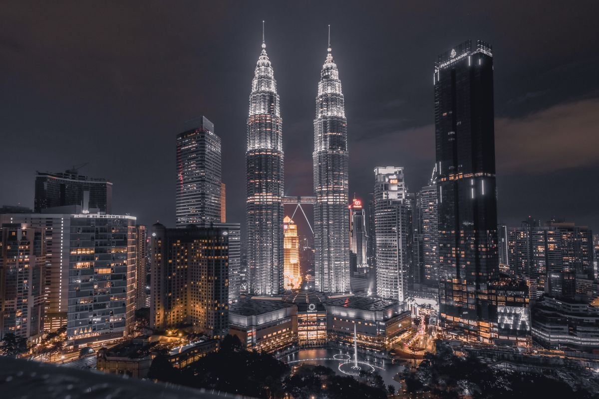 Kuala Lumpur skyline at night with the illuminated Petronas Twin Towers among high-rise buildings