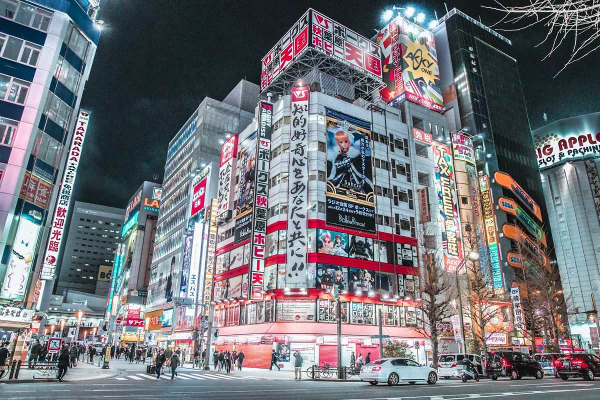 Neon-lit buildings and traffic at a busy Tokyo intersection at night