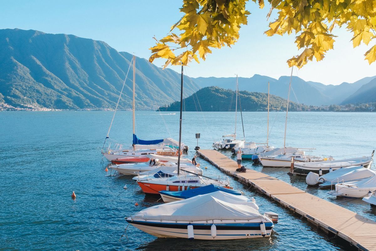 Small boats moored beside a wooden pier on a calm lake with mountains behind