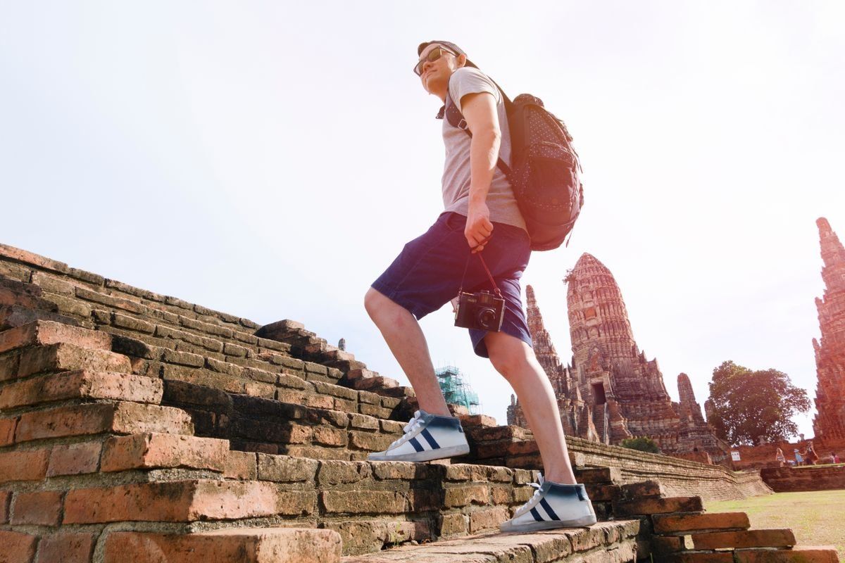 Traveler with a backpack climbing brick steps at a historic temple site