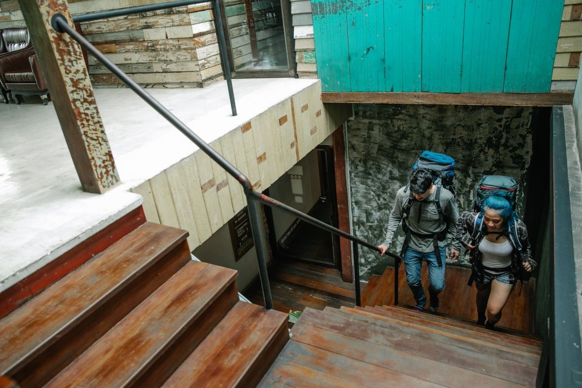 Two backpackers climbing indoor stairs with large hiking packs