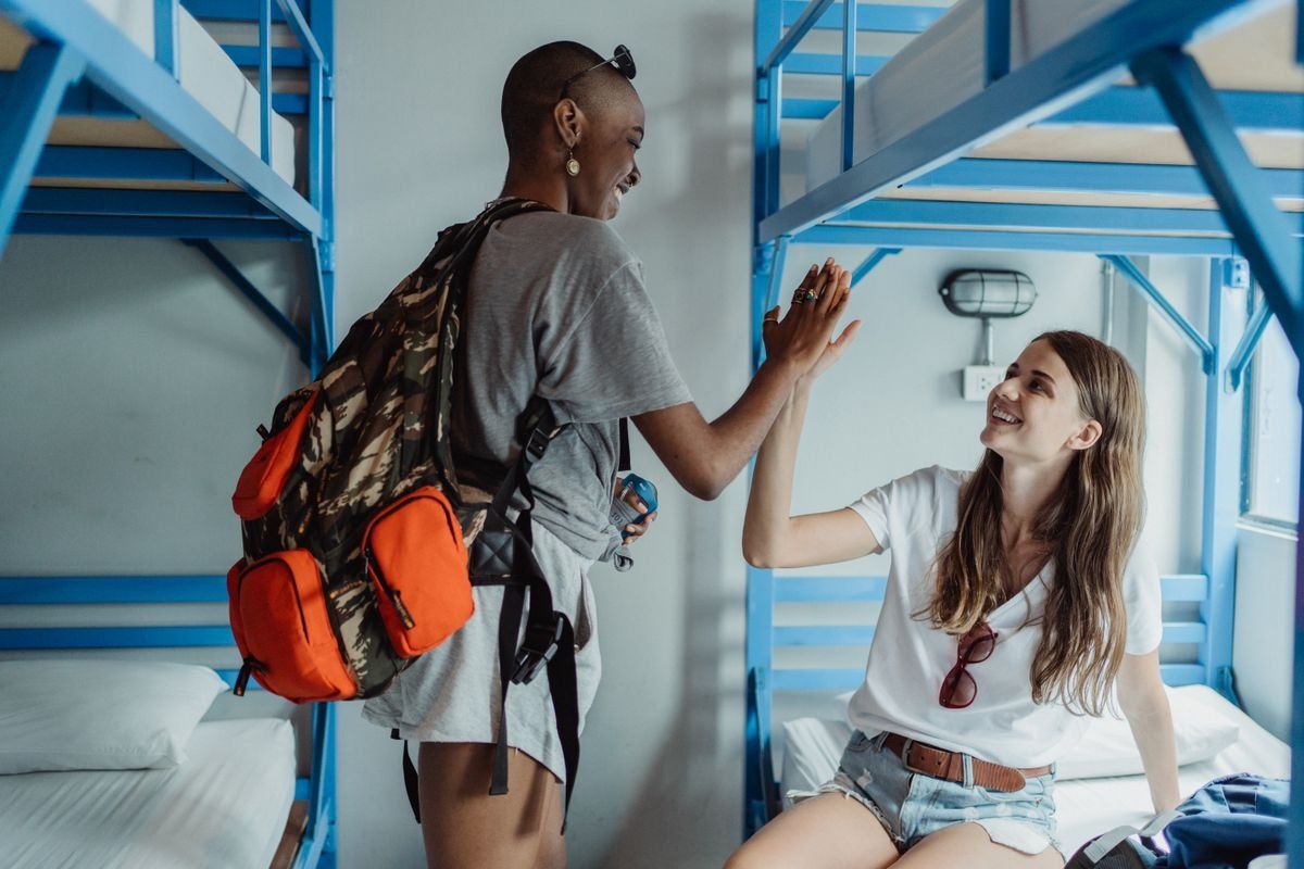 Two women high-fiving between bunk beds in a shared dorm room