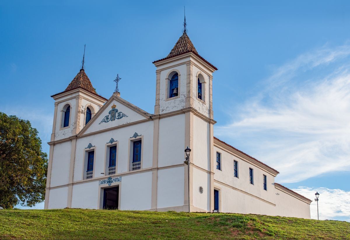 White basilica with twin bell towers on a grassy slope beneath a clear blue sky