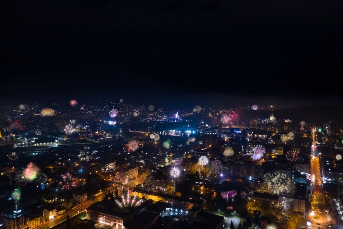 Aerial night view of fireworks scattered across Podgorica above illuminated streets and buildings