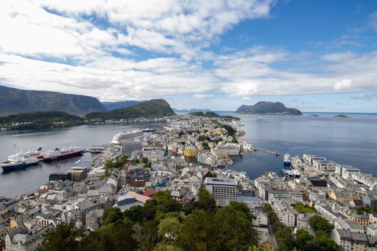 Aerial view of Ålesund harbor with ships, compact town and mountains across the water