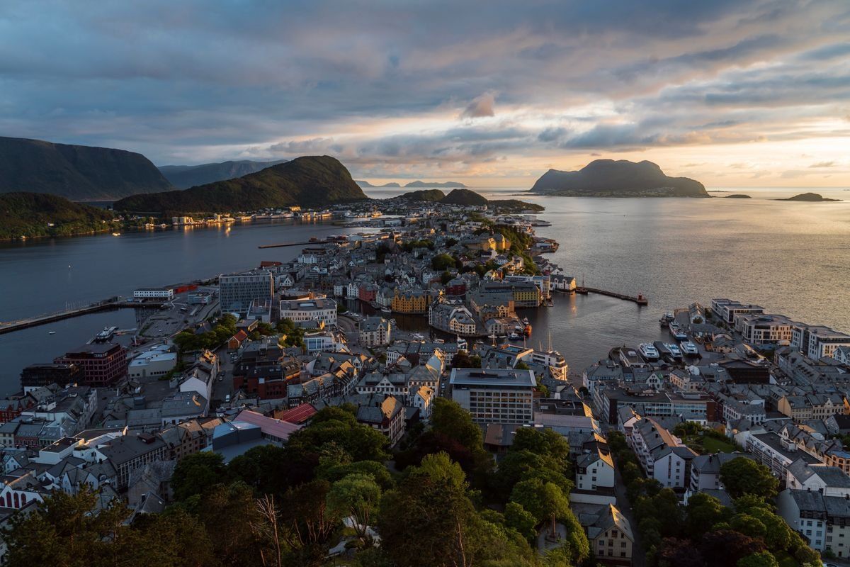 Aerial view of Ålesund at sunset with clustered buildings, harbor and surrounding islands