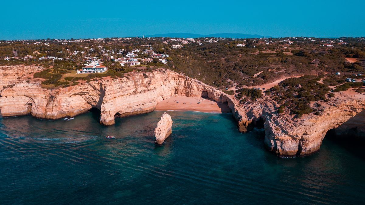 Aerial view of rugged sea cliffs, a small cove and turquoise water along the coast