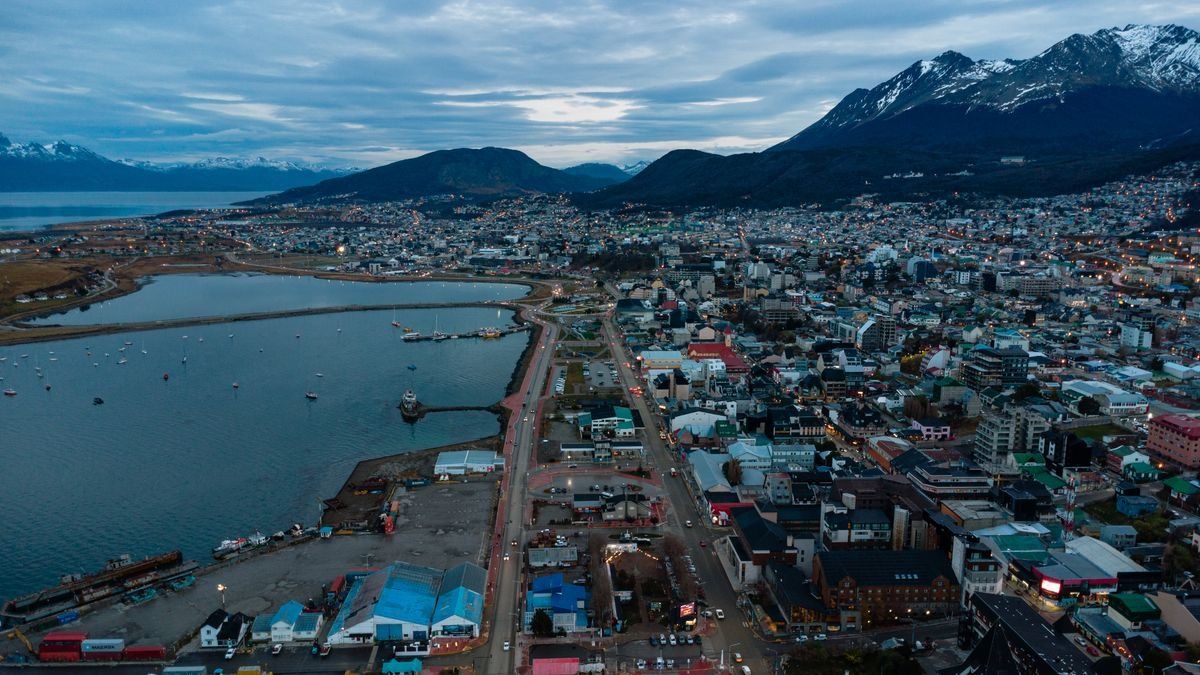 Aerial view of Ushuaia harbor and city at twilight with dark mountains behind