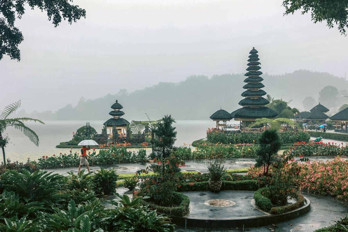 Balinese lakeside temple with tiered shrines, flower gardens and misty hills in the background