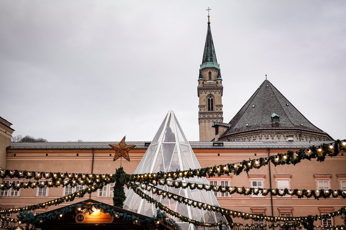 Christmas market garlands and glass tree structure with historic buildings and church tower