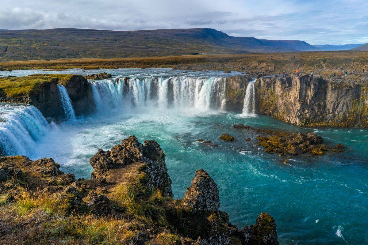 Godafoss waterfall pouring into a turquoise river between rocky cliffs and open highlands