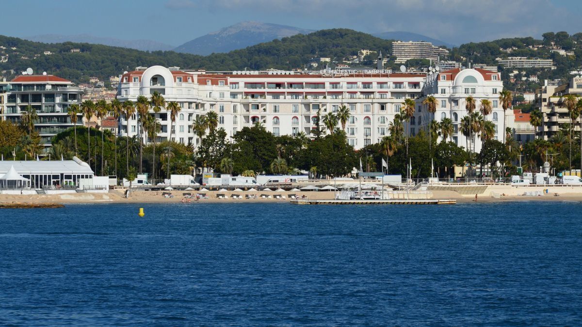 Large white beachfront hotel across calm blue water in Cannes