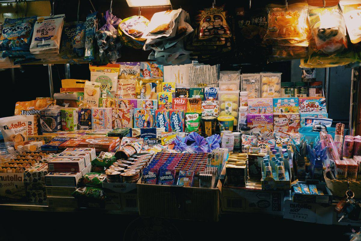 Night market stall packed with colorful sweets, snacks, and packaged treats