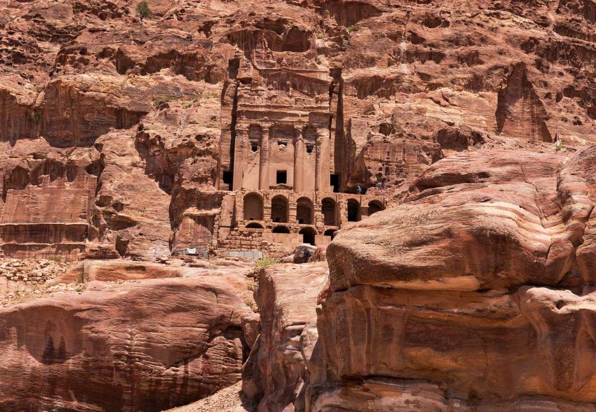 Rock-cut tomb facade carved into rose sandstone cliffs in Petra