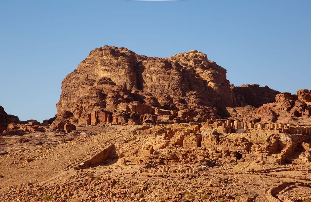 Rocky hillside with ancient stone ruins and carved structures in Petra