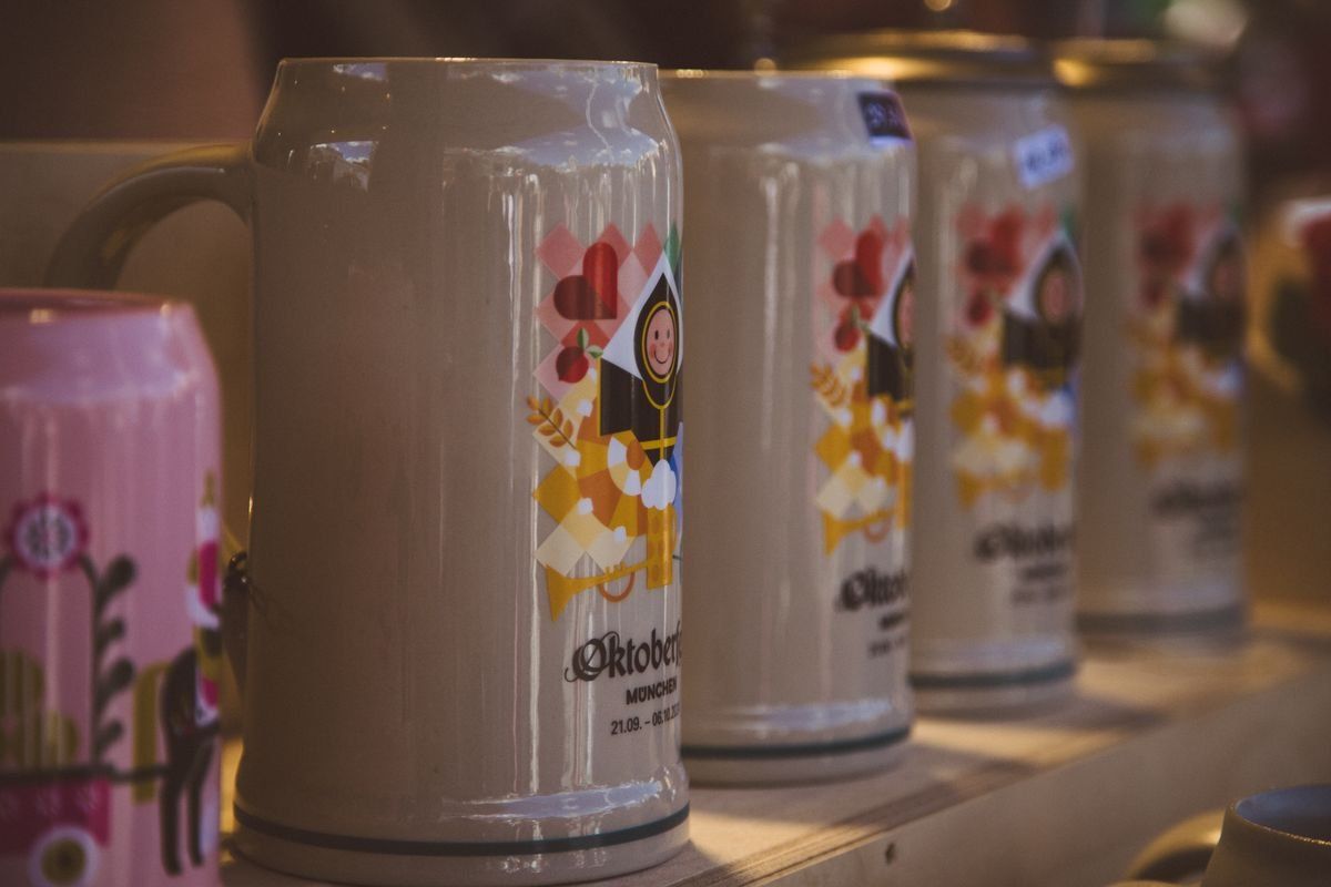 Row of decorative ceramic beer steins displayed on a wooden shelf
