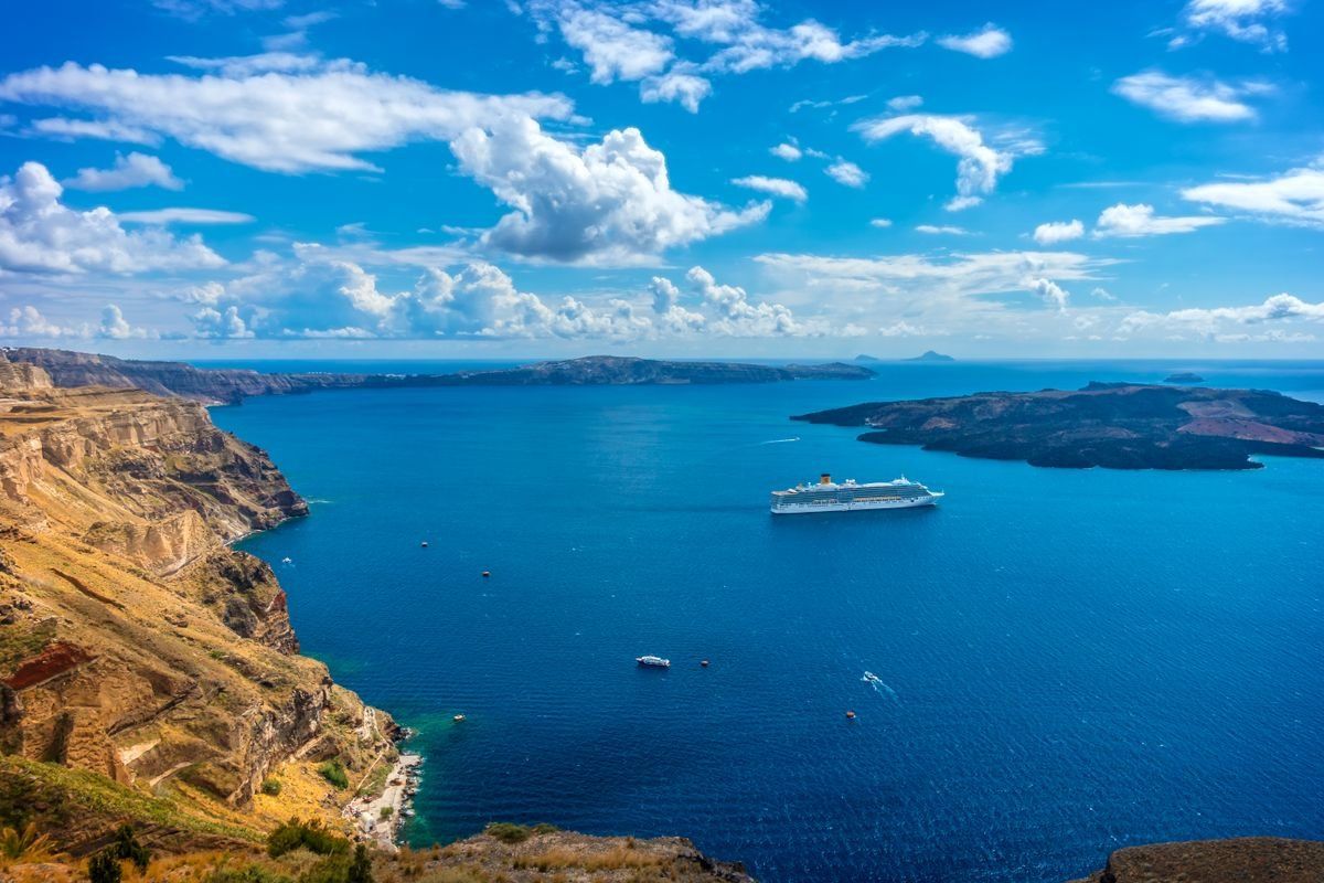 Santorini caldera with steep cliffs, deep blue sea, and a cruise ship offshore