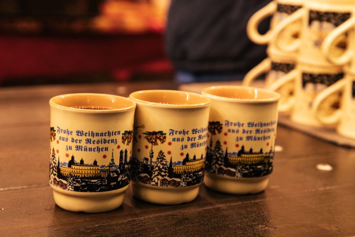 Three festive ceramic mugs on a counter at a Christmas market stall