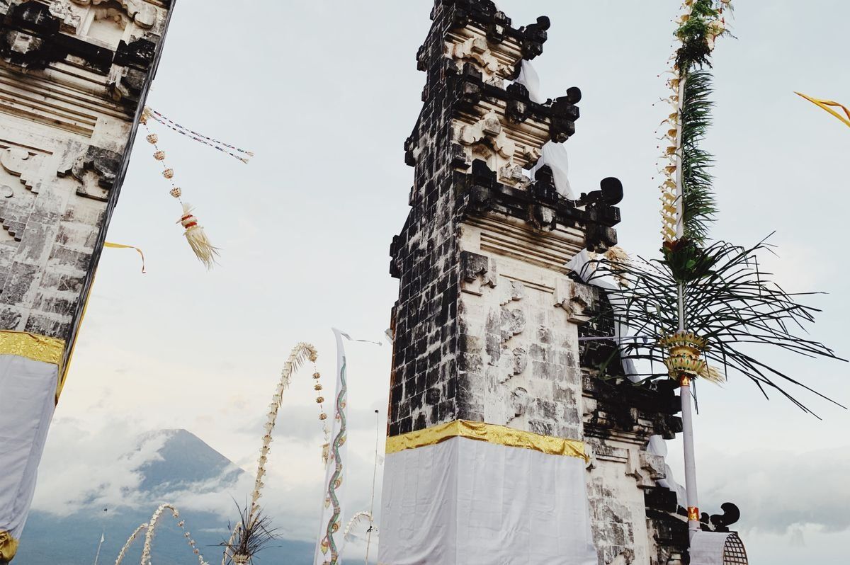 Traditional Balinese temple gate with decorated poles and Mount Agung in the background