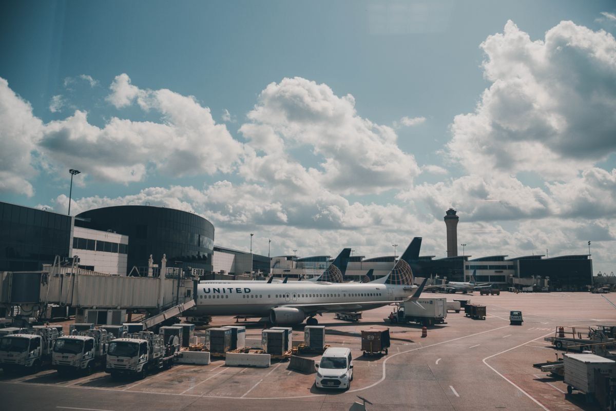 United airplane parked at an airport gate with service vehicles under a cloudy sky