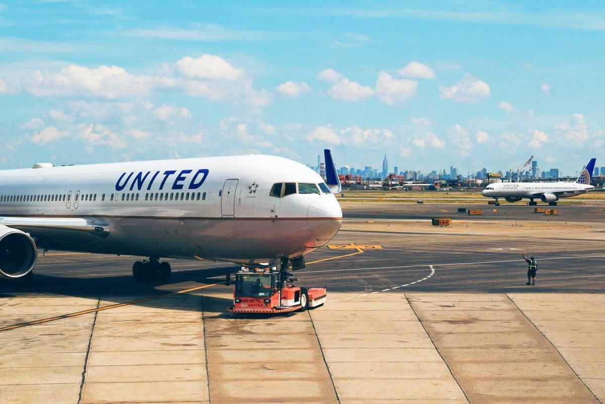 United airplane on the tarmac with another jet and distant city skyline in the background