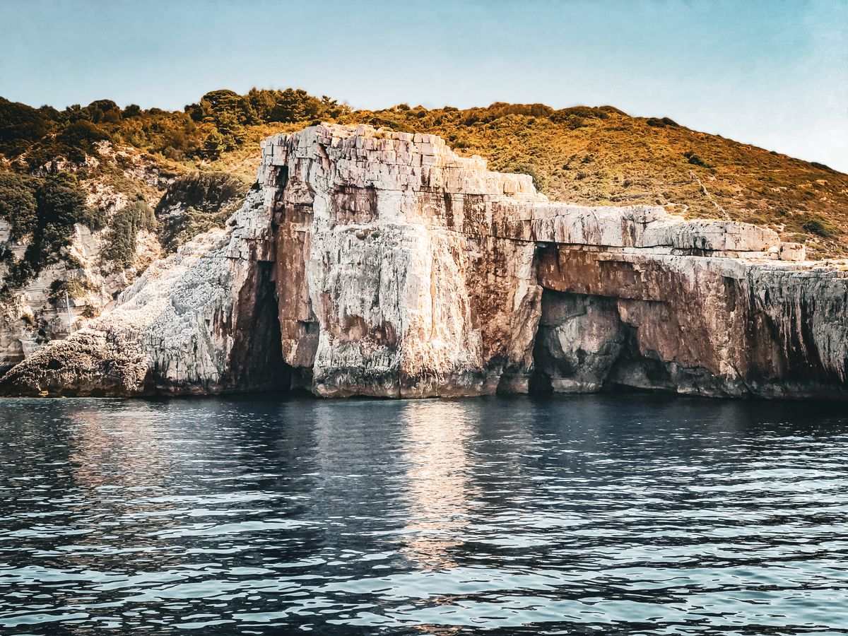 White coastal cliffs reflected in calm sea water along the Greek shoreline